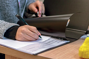 Staff in office writing on a printed document